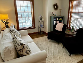 Carey's therapy office with a couch, windows, and warm lighting